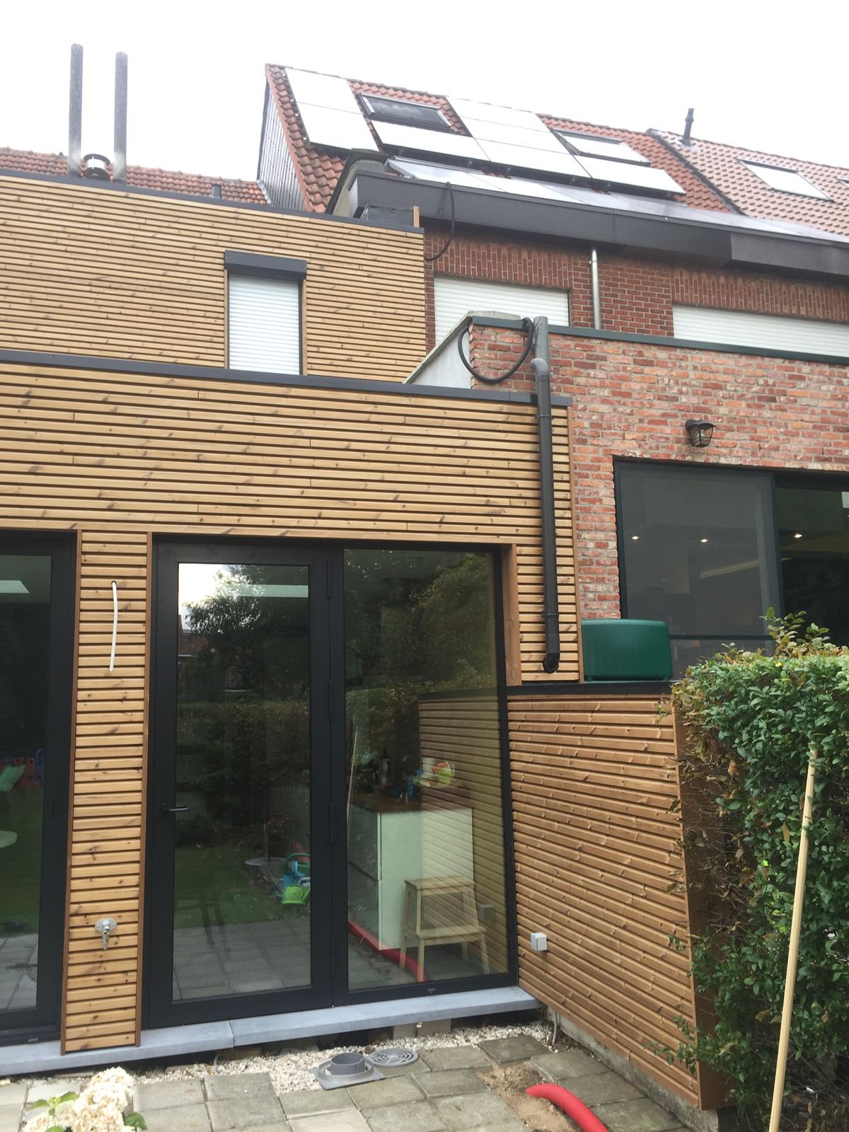 Achtergevel met houten bekleding en grote glazen deuren